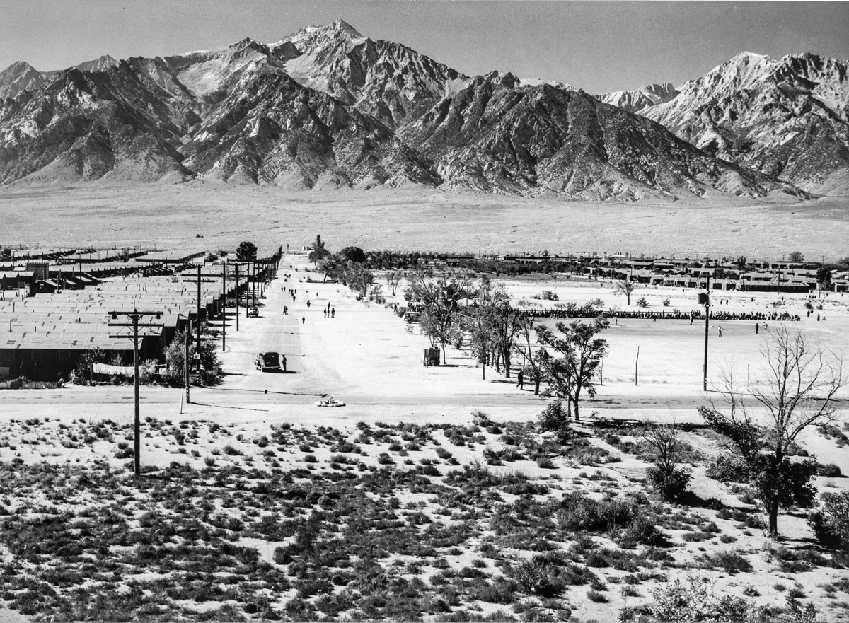 A view down 6th street at the Manzanar Relocation Center for deported Japanese-Americans, California, 1943. Barracks of Block 19 are on the left, the baseball field is on the right, and Mt Williamson is beyond.