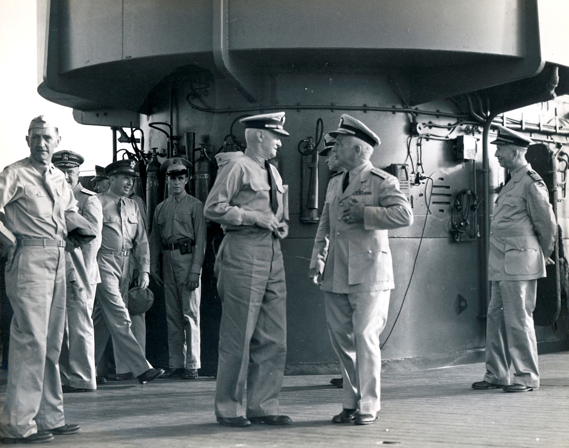 United States Navy Admiral Chester Nimitz, left center, speaking to Rear Admiral Aubrey Fitch on the flight deck of USS Saratoga at Pearl Harbor while an Army Major General, far left, looks on, circa 1942.