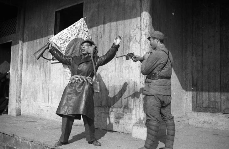 Chinese war correspondent mocking surrendering Japanese soldiers, Changde, Hunan Province, China, 25 Dec 1943, photo 2 of 2; note Arisaka Type 38 rifle, signed flag, helmet, and Type 91 or Type 95 gas mask