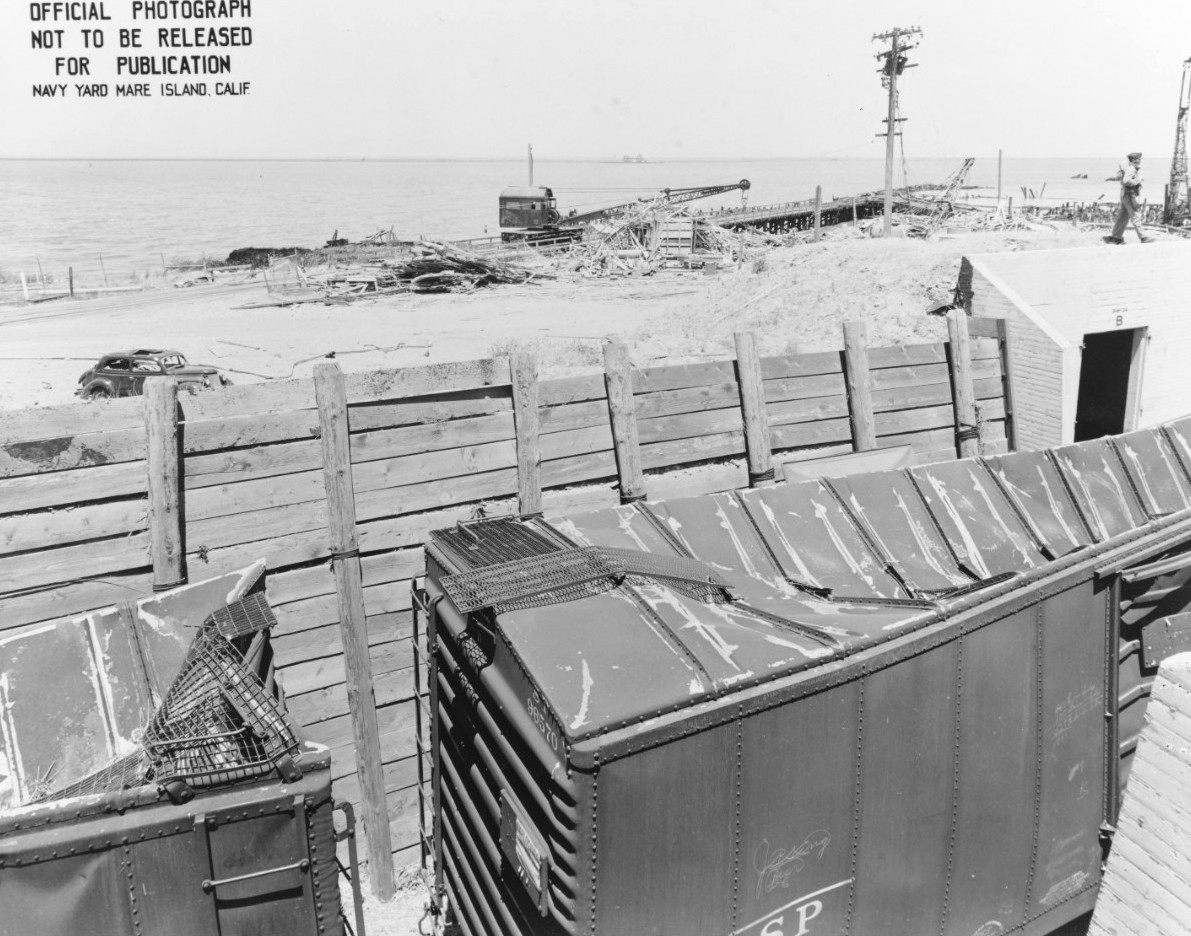 Railroad cars laden with munitions in a revetment at Port Chicago, California, United States damaged by a massive explosion the night before, 18 Jul 1944.