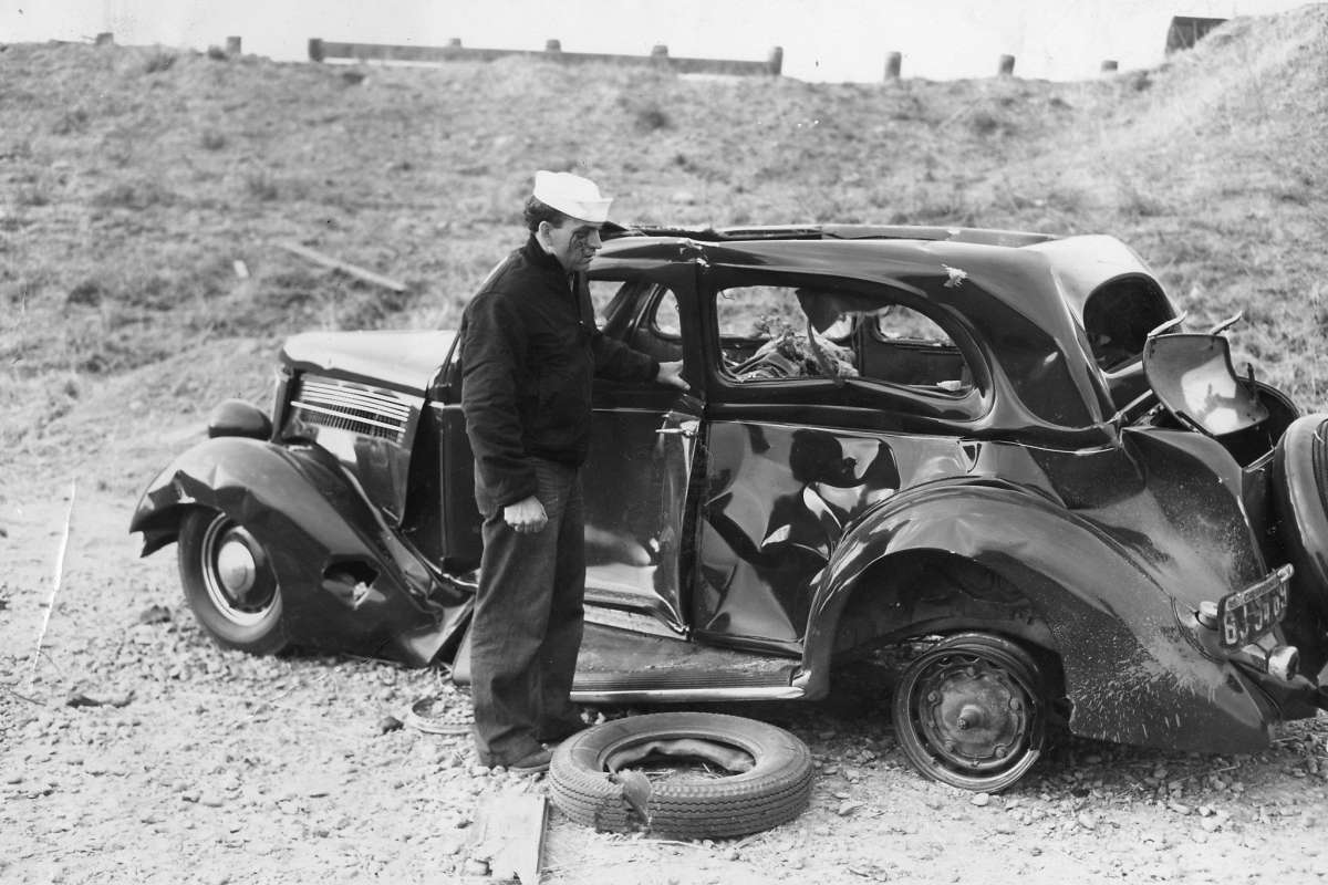 Sailor with bloody face standing next to the car the he was driving when they were both blown off the road by a massive munitions explosion at Port Chicago, California, United States, on 17 Jul 1944. 18 Jul 1944 photo.