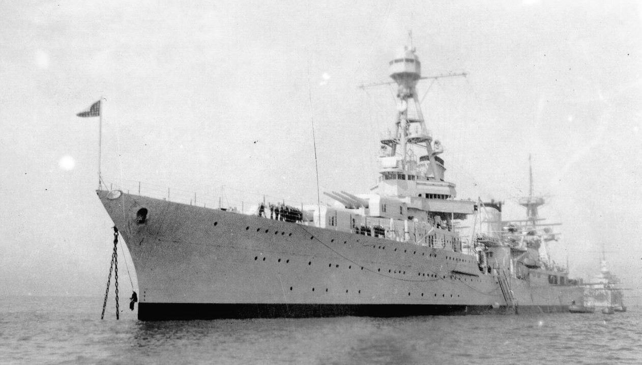 USS Northampton at anchor, location unknown, 1930s. Note the sailor in the Bosun’s Chair hanging from the bow.