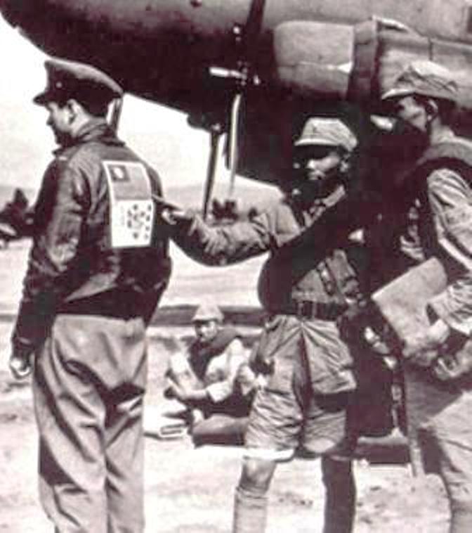 Nationalist-Chinese soldiers looking at the Blood Chit on the back of an American officer at a Chinese airfield, 1942. Note the C-47 Skytrain.