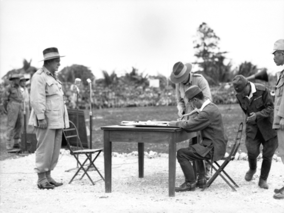 Australian General Sir Thomas Blamey witnessing Japanese Second Army Lt General Fusataro Teshima signing the instrument of surrender for Japanese forces throughout the Dutch East Indies, Morotai, 9 Sep 1945. Photo 1 of 2
