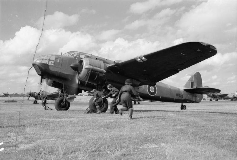 WAAF flight mechanics pulling the chocks from the wheels of a Beaufort Mark I aircraft of No. 51 Operational Training Unit before a training flight from RAF Cranfield, Bedfordshire, England, United Kingdom, 1944; note a Beaufighter Mark VI aircraft in background
