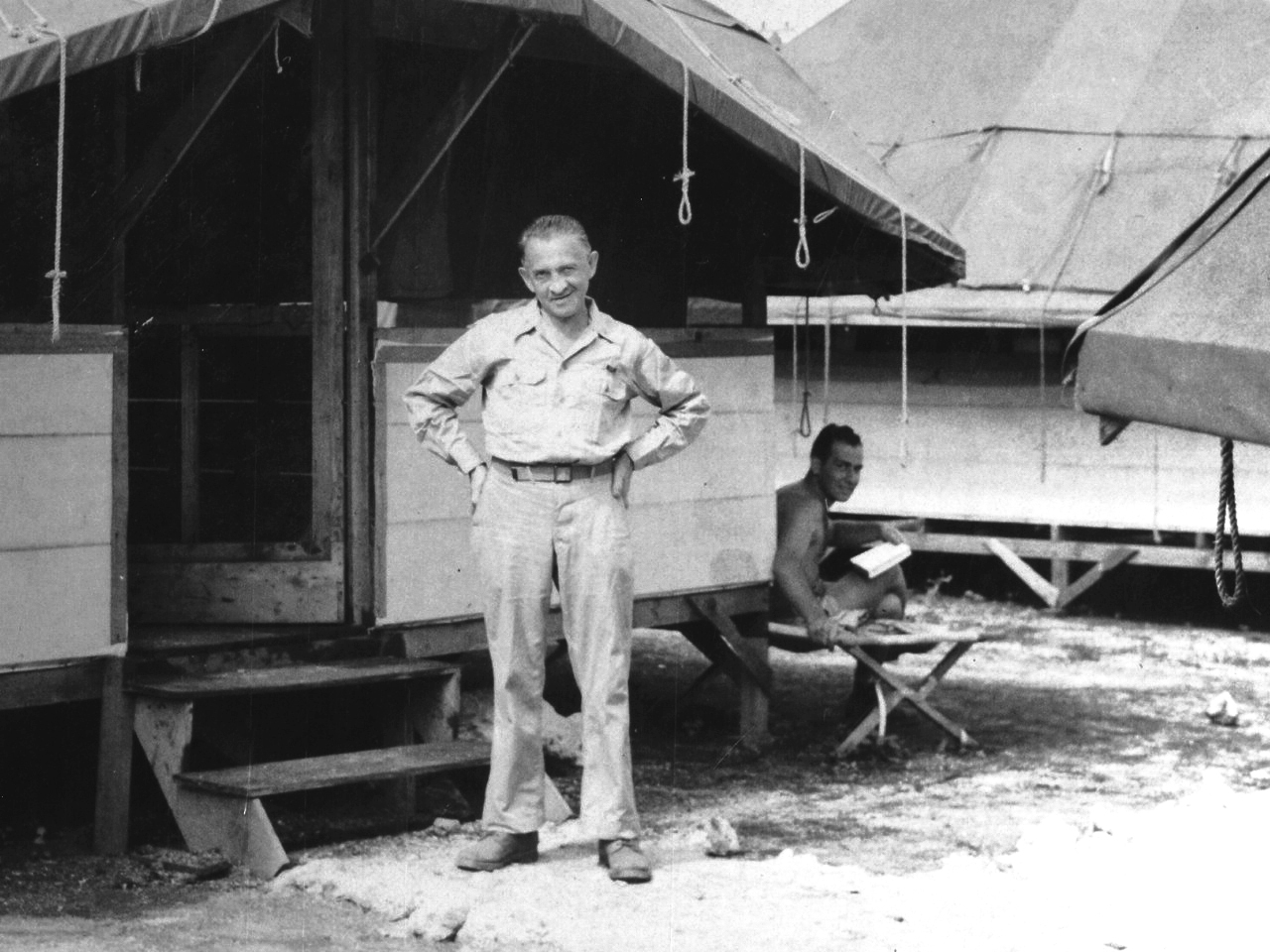 William Laurence in front of a hut on Tinian, Mariana Islands, Aug 1945. TSgt Jesse Kupferberg is at right on the cot.