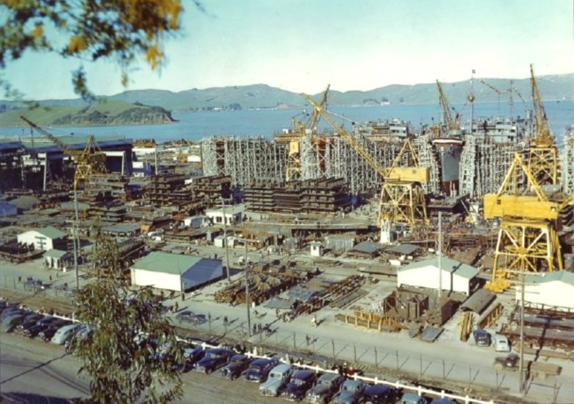 Color photo of work underway at the Marinship yard, Sausalito, California, United States, 15 Apr 1944. Oil tanker Mission San Carlos has her bow draped in bunting for her launch later that day.