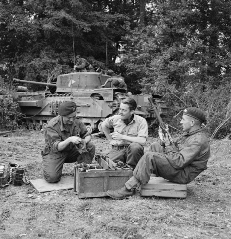 Commanding officer Lieutenant Fathergill of B Squadron, 107th Regiment Royal Armoured Corps, UK 34th Tank Brigade cleaning a BESA machine gun with two other members of his Churchill tank crew, France, 17 Jul 1944