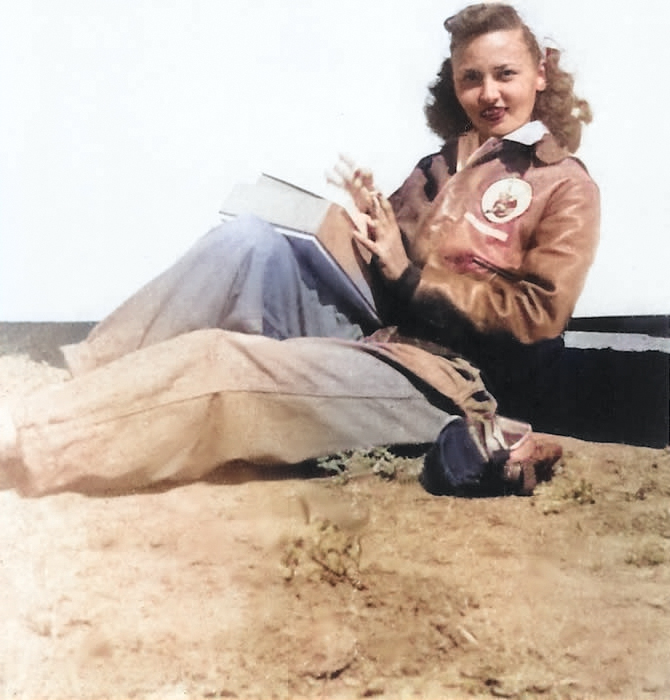 Posed photo of a WASP pilot in flight gear and leather flying jacket showing WASP “Fifinella” patch, 1944, location unknown but probably Avenger Field, Sweetwater, Texas, United States. [Colorized by WW2DB]