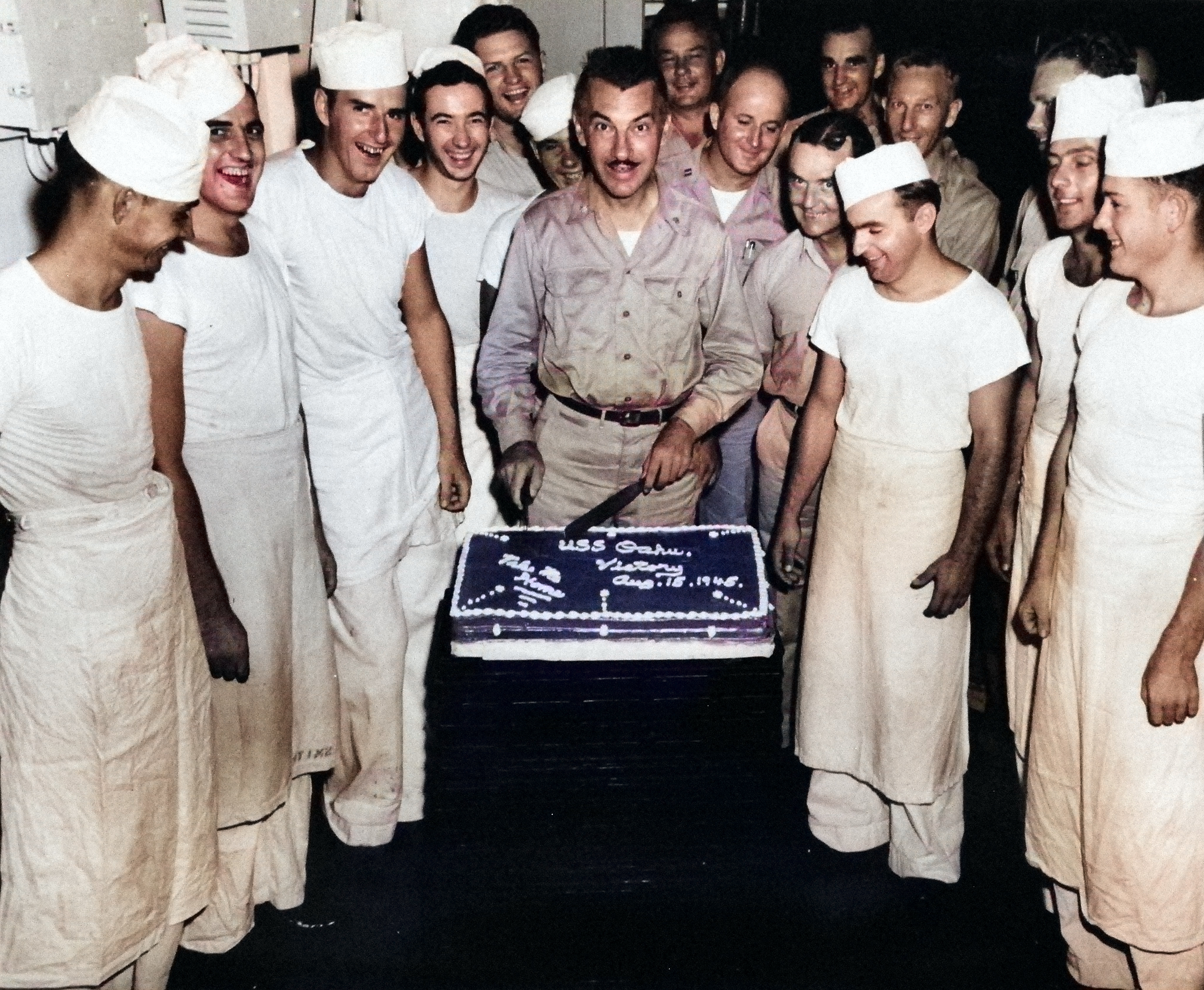 Commander A. M. Loker celebrating victory with cake aboard USS Oahu while at Eniwetok, Marshall Islands, 15 Aug 1945 [Colorized by WW2DB]