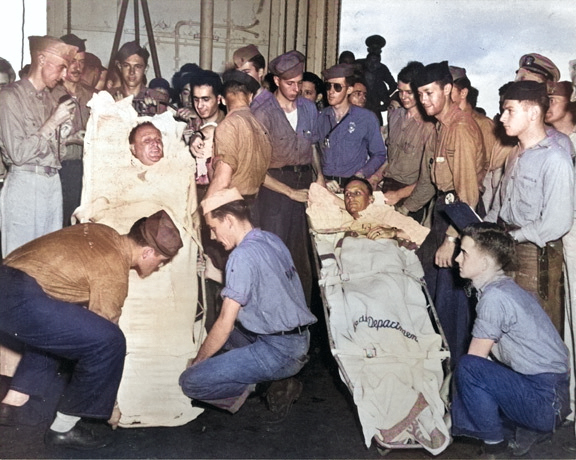 Capt Dixie Kiefer (left) and executive officer Cdr Willian Burch, both badly injured in an air attack four days earlier, being prepared for transfer from Ticonderoga to the hospital ship Samaritan at Ulithi, 25 Jan 1945 [Colorized by WW2DB]