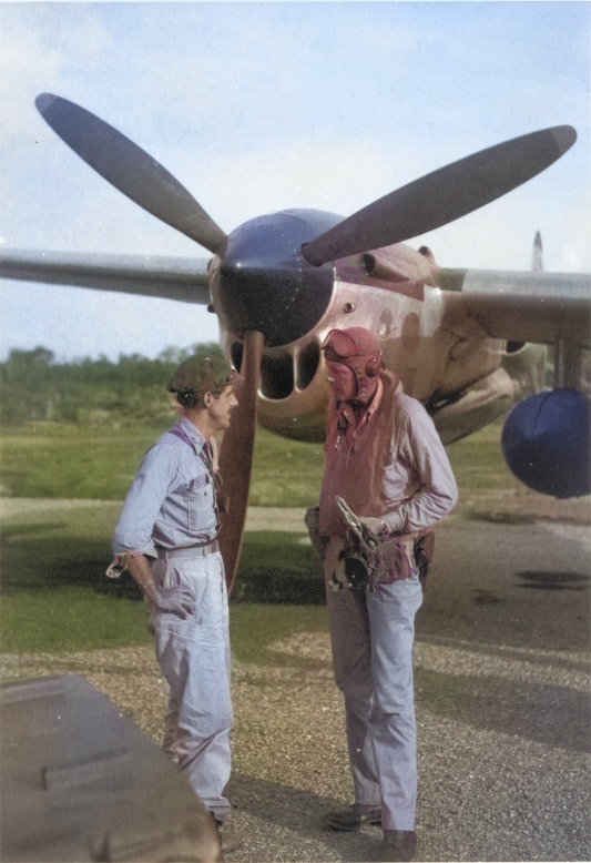 USAAF pilots Thomas McGuire and Charles Lindbergh after returning from a combat mission, at Biak Island off New Guinea, circa Jul 1944; note P-38 Lightning aircraft, possibly McGuire's, in background [Colorized by WW2DB]