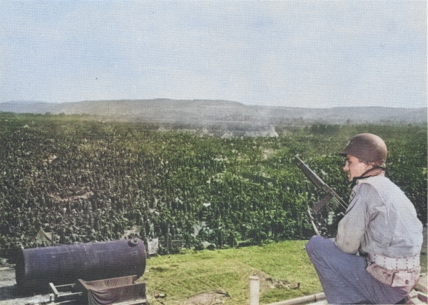 American soldier guarding a corner of a German prisoners of war camp near Remagen, Germany, 25 Apr 1945 [Colorized by WW2DB]