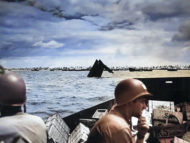 US Coast Guard personnel transporting supplies to Tarawa, Gilbert Islands, circa 20-23 Nov 1943; note the wreck of an American LCVP in center of photo [Colorized by WW2DB]