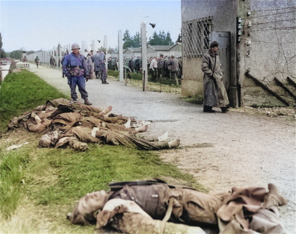 An American soldier standing beside the bodies of SS personnel shot by US troops during the liberation of Dachau Concentration Camp, Germany, 29-30 Apr 1945 [Colorized by WW2DB]