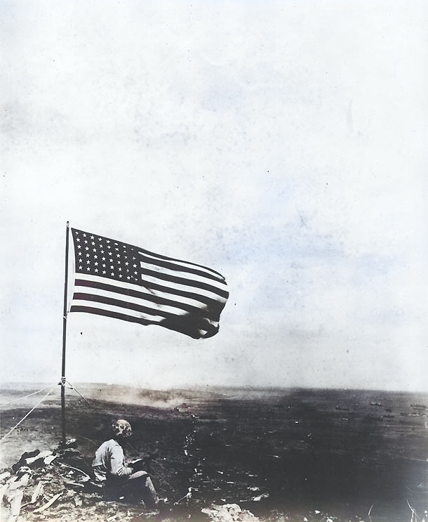 An American Marine sat beneath the American flag atop Mount Suribachi, Iwo Jima, Japan, 23 Feb 1945 [Colorized by WW2DB]