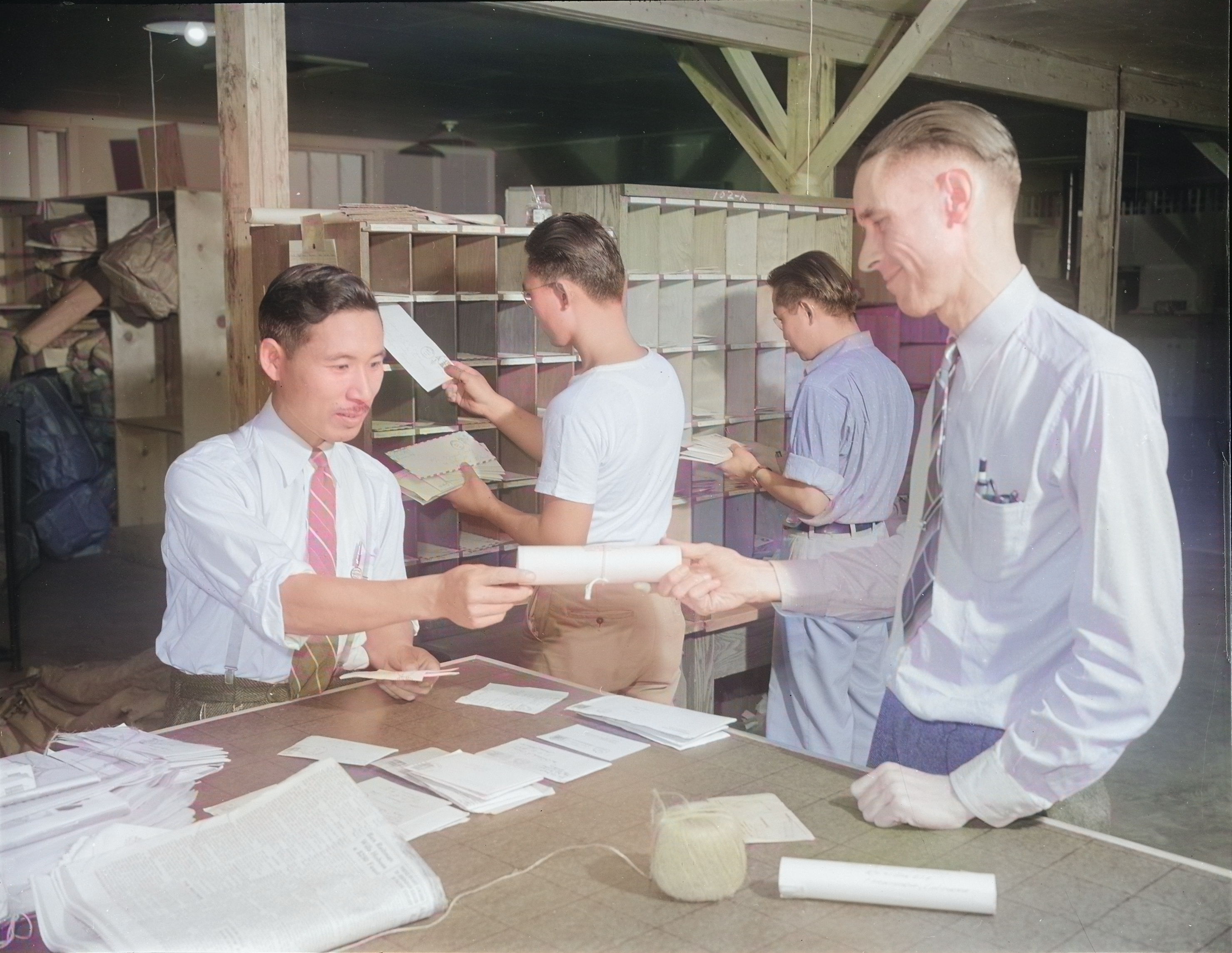 Postmaster Fred Paris with workers at the Jerome War Relocation Center post office, Arkansas, United States, 20 Nov 1942 [Colorized by WW2DB]