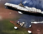 Crew of the USS Bennington honoring the sunken USS Arizona as she passes in Pearl Harbor, Hawaii, 31 May 1958. Note that Bennington now has an angled flight deck and a starboard side deck edge aircraft elevator.