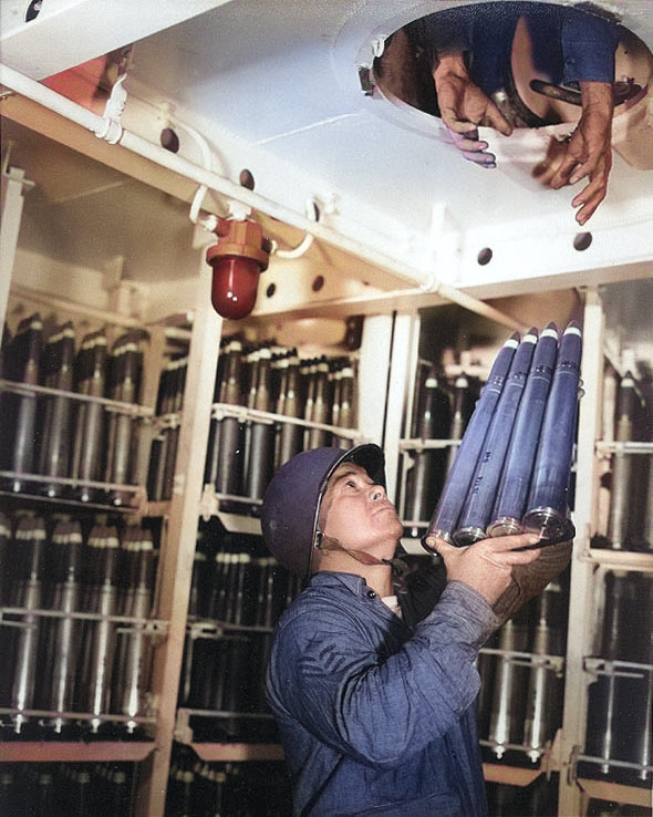 Gunner's Mate First Class Carrick N. Thomas passed a clip of four 40mm rounds through a hatch in a 40mm handling room of Alaska, off Iwo Jima, 6 Mar 1945 [Colorized by WW2DB]