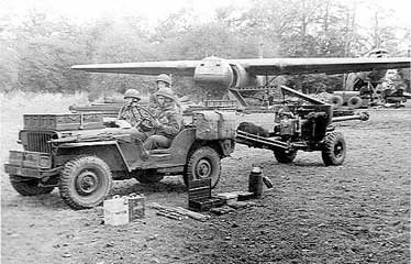 British troops towing a field gun with jeep, with ammunition boxes on the hood, England, United Kingdom, 1944; note Horsa glider in background