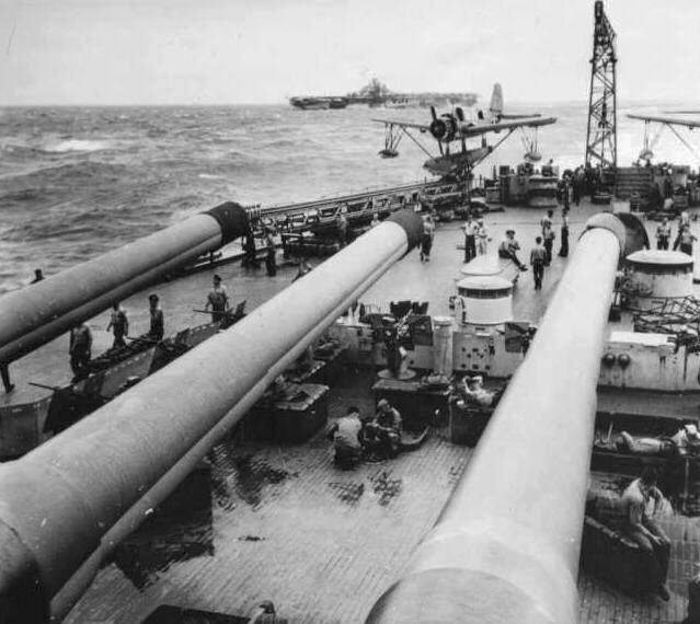 OS2U Kingfisher aircraft on the fantail of USS New Jersey or USS Wisconsin, off Taiwan, 18 Jan 1945; note 16-inch guns in foreground and USS Hornet in background