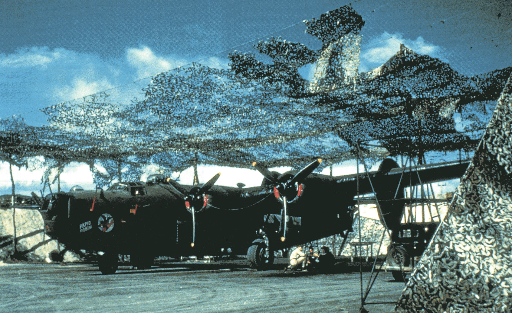 B-24 Liberator 'Rapid Robin' of the 431st Bomb Squadron parked under camouflage netting at Bellows Field, Oahu, US Territory of Hawaii, Aug or Sep 1943
