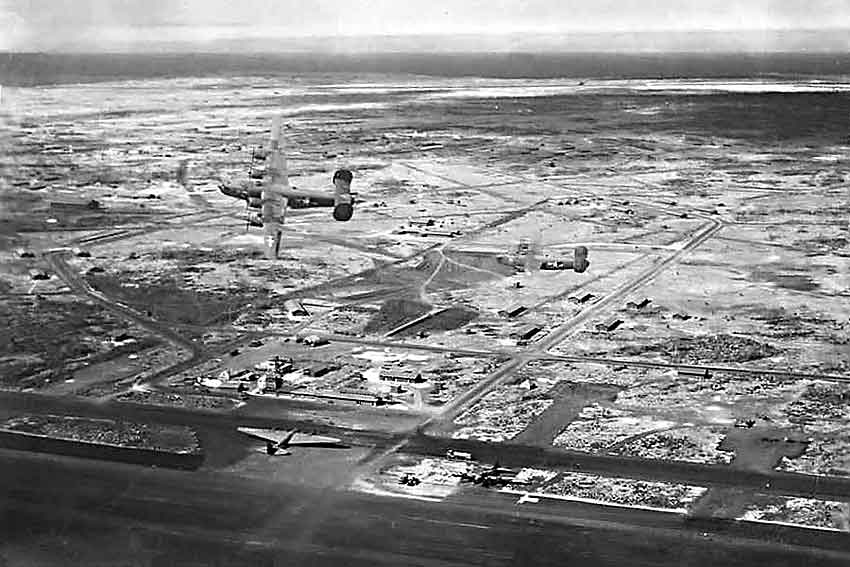 B-24 bombers in flight over the US Army airfield on Baltra, Galápagos Islands, 1940s; note XB-15 bomber on the ground