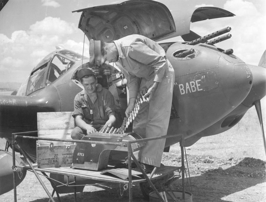 USAAF armorer 1st Lieutenant H. A. Blood examining the 20mm cannon ammunition of P-38 Lightning aircraft 'Babe', date unknown
