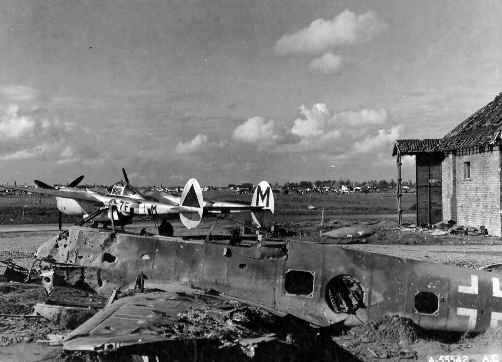 P-38J Lightning aircraft of 370th Fighter Group, US 485th Fighter Squadron at the former Luftwaffe night fighter base at Florennes, Belgium, Oct-Dec 1944; note wrecked Me 210 aircraft in foreground