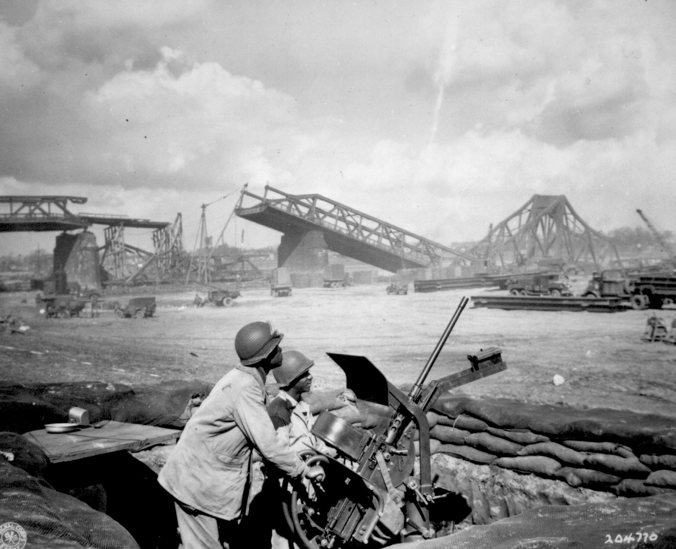 US Army African-American Privates George Cofield and Howard Davis manning an anti-aircraft weapon near a bridge under construction over the Rhine River, 30 Mar 1945