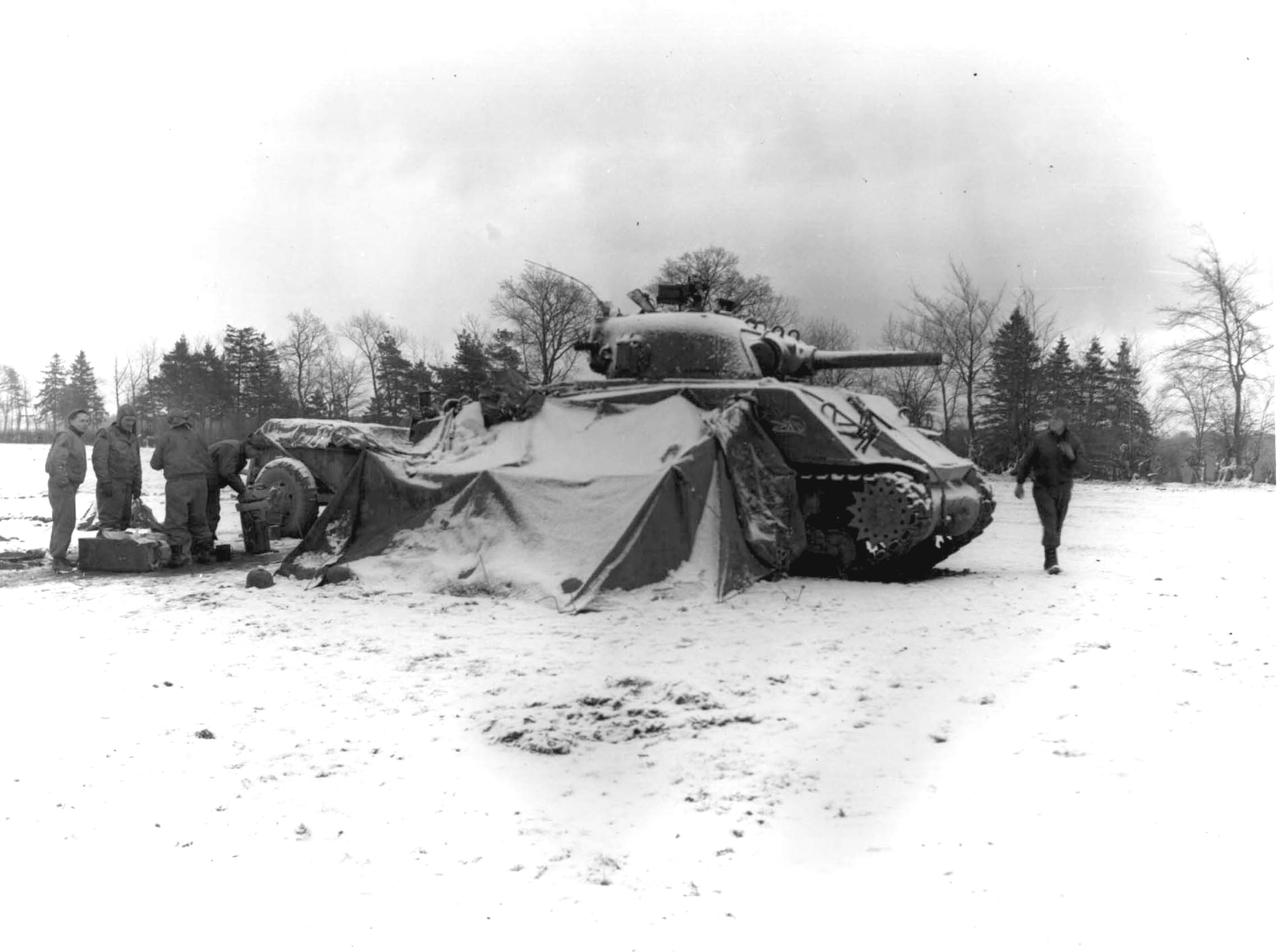 US 5th Armored Regiment tankers gathering around a fire and opening Christmas presents, near Eupen, Belgium, 30 Dec 1944; note M4 Sherman tank
