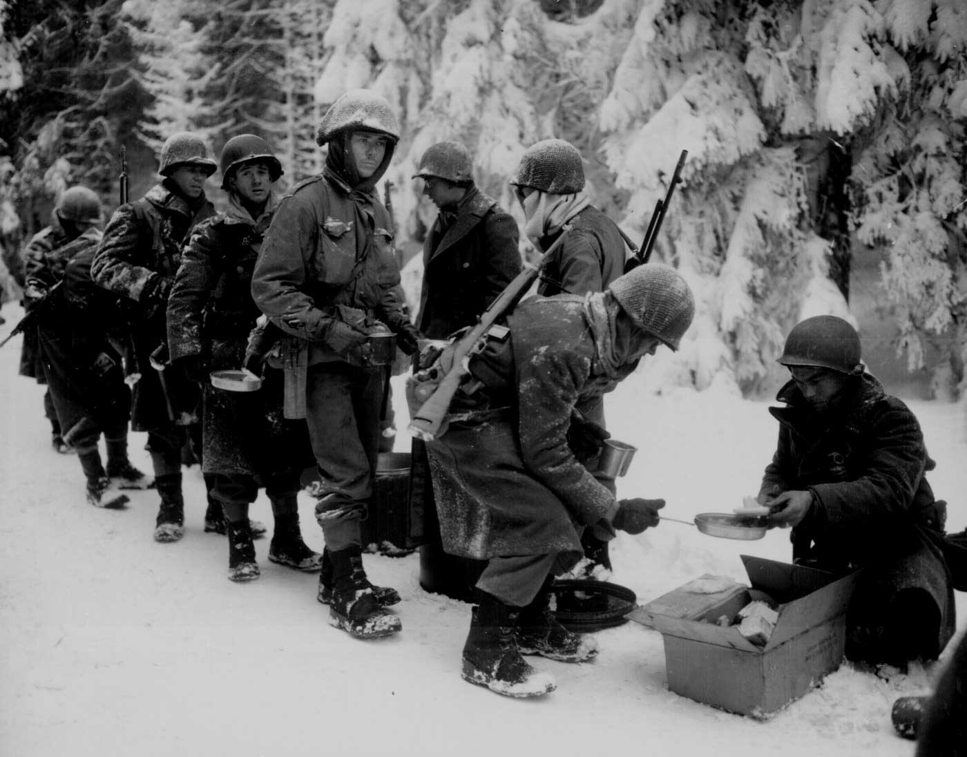 Men of the US 347th Infantry Regiment taking a meal break while en route to La Roche, Belgium, 13 Jan 1945