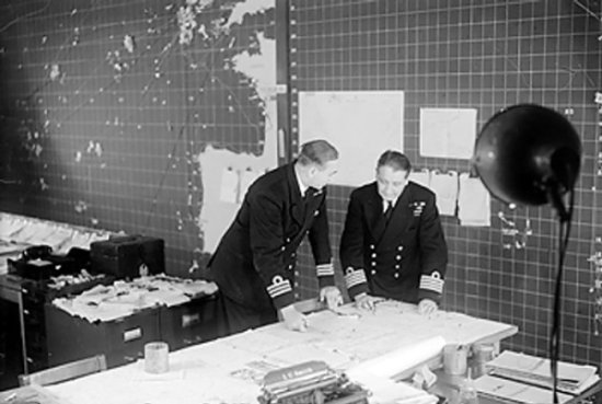 British Royal Navy Commander Cross reviewing a convoy movement map with Captain Lake, Derby House, Liverpool, England, United Kingdom, 26 or 27 Sep 1944
