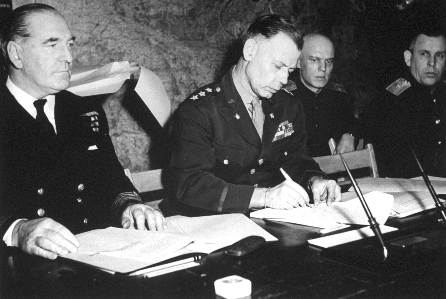 LtGen Bedell Smith signing the documents of Germany’s surrender, Reims, France, 7 May 1945. British Adm Harold Burrough is on the left. Soviet Gen Ivan Susloparov is on the extreme right.