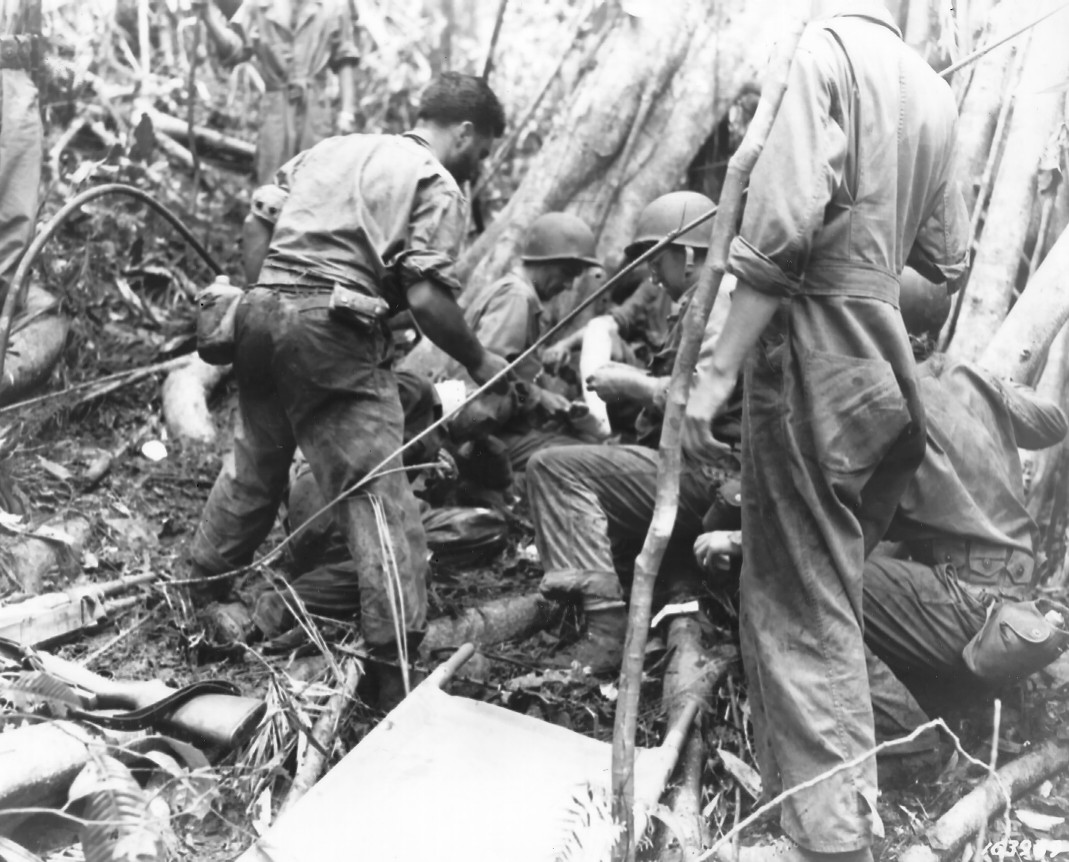 Litter bearers of the Medical Battalion of US 25th Division giving first aid to two men wounded by grenades, Guadalcanal, 10 Jan 1943
