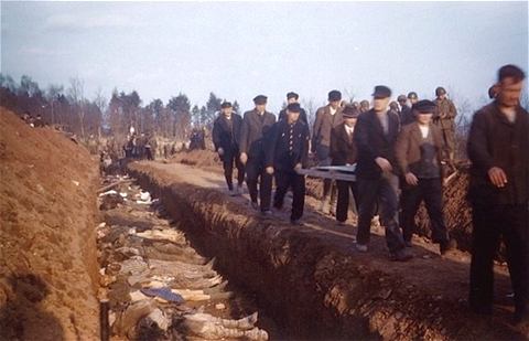 Supervised by American soldiers, German civilians from the town of Nordhausen, Germany bury the corpses of prisoners found at the Mittelbau-Dora concentration camp in mass graves, mid-Apr 1945