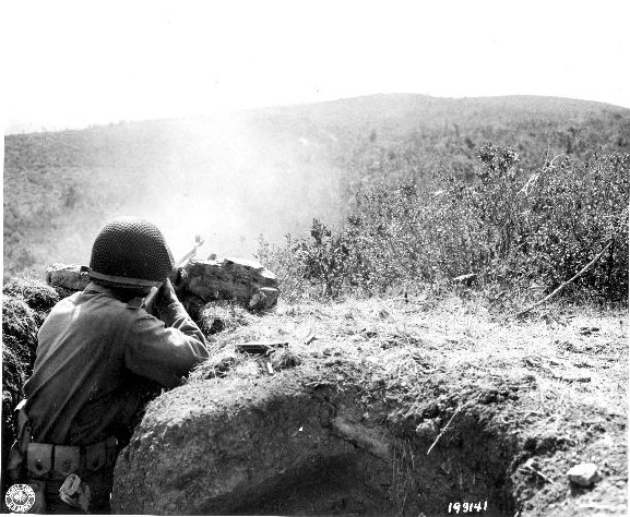 Japanese-American soldier of 100th Infantry Battalion, US 442nd Regimental Combat Team firing at a suspected German sniper position, Montenero area, Italy, 7 Aug 1944