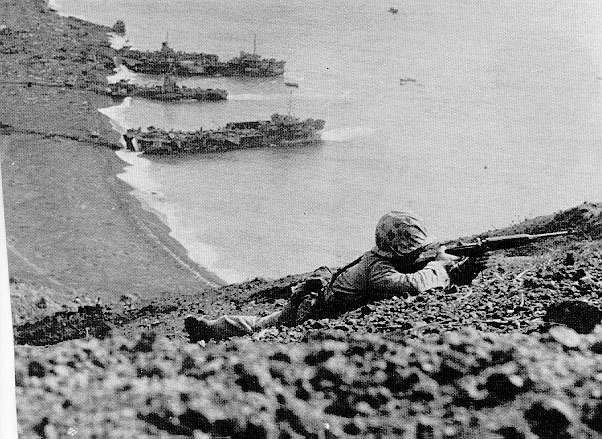 US Marine on Mount Suribachi, with landing craft in the background, Iwo Jima, Japan, 19-23 Feb 1945
