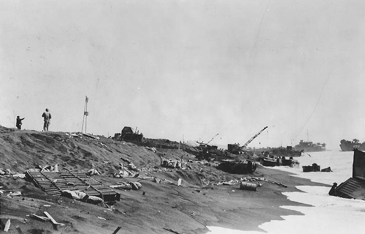 Beach scene at Iwo Jima about two or three days after the initial landings, showing the beach cluttered with wrecked LVTs, landing craft and other debris, circa 21-22 Feb 1945