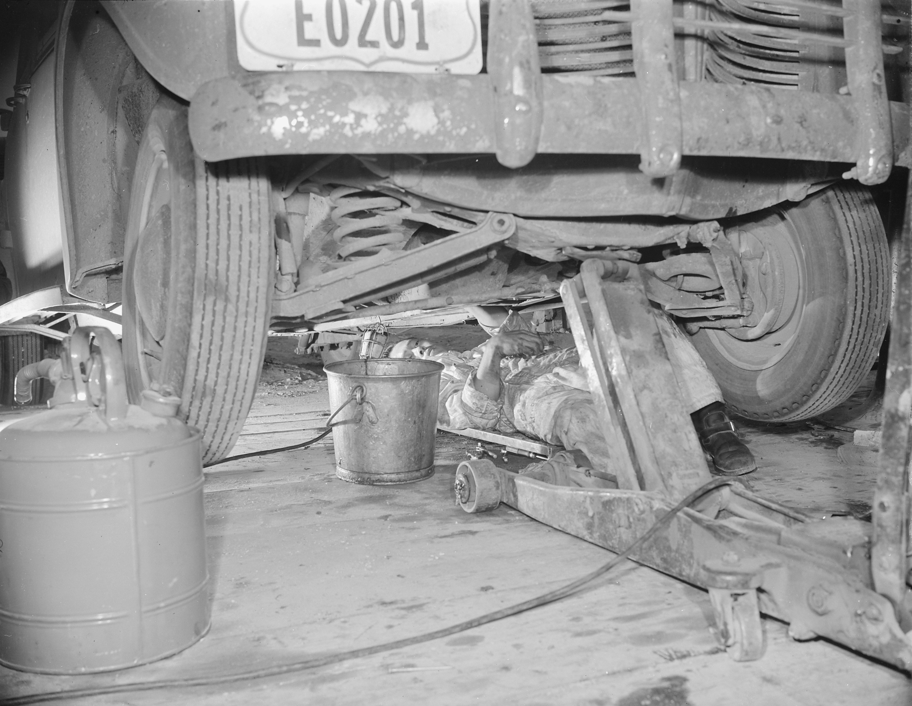 Japanese-American mechanic working under a vehicle, Jerome War Relocation Center, Arkansas, United States, 17 Nov 1942