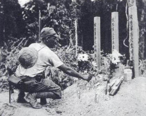 A Japanese soldier tending graves of fallen comrades, Malaya, circa Dec 1941-Feb 1942