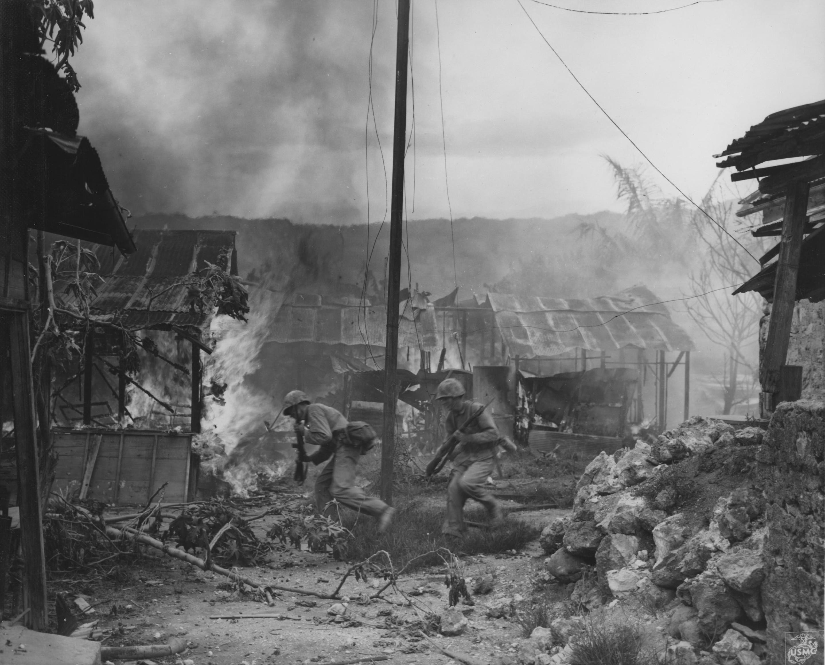 US Marines running through streets of Garapan while engaging in street fighting, Saipan, Mariana Islands, 3 Jul 1944
