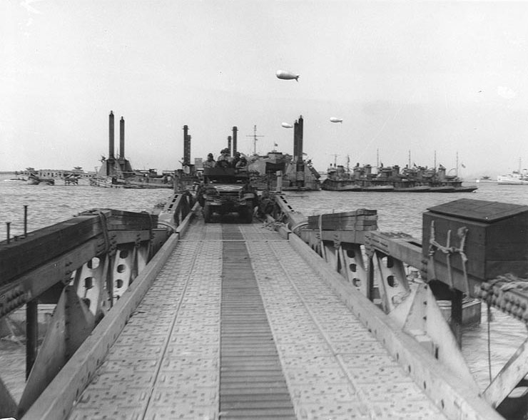 Floating causeway of the Mulberry artificial harbor off Omaha Beach, Normandy, 16 Jun 1944, with a half-track rolling toward the shore