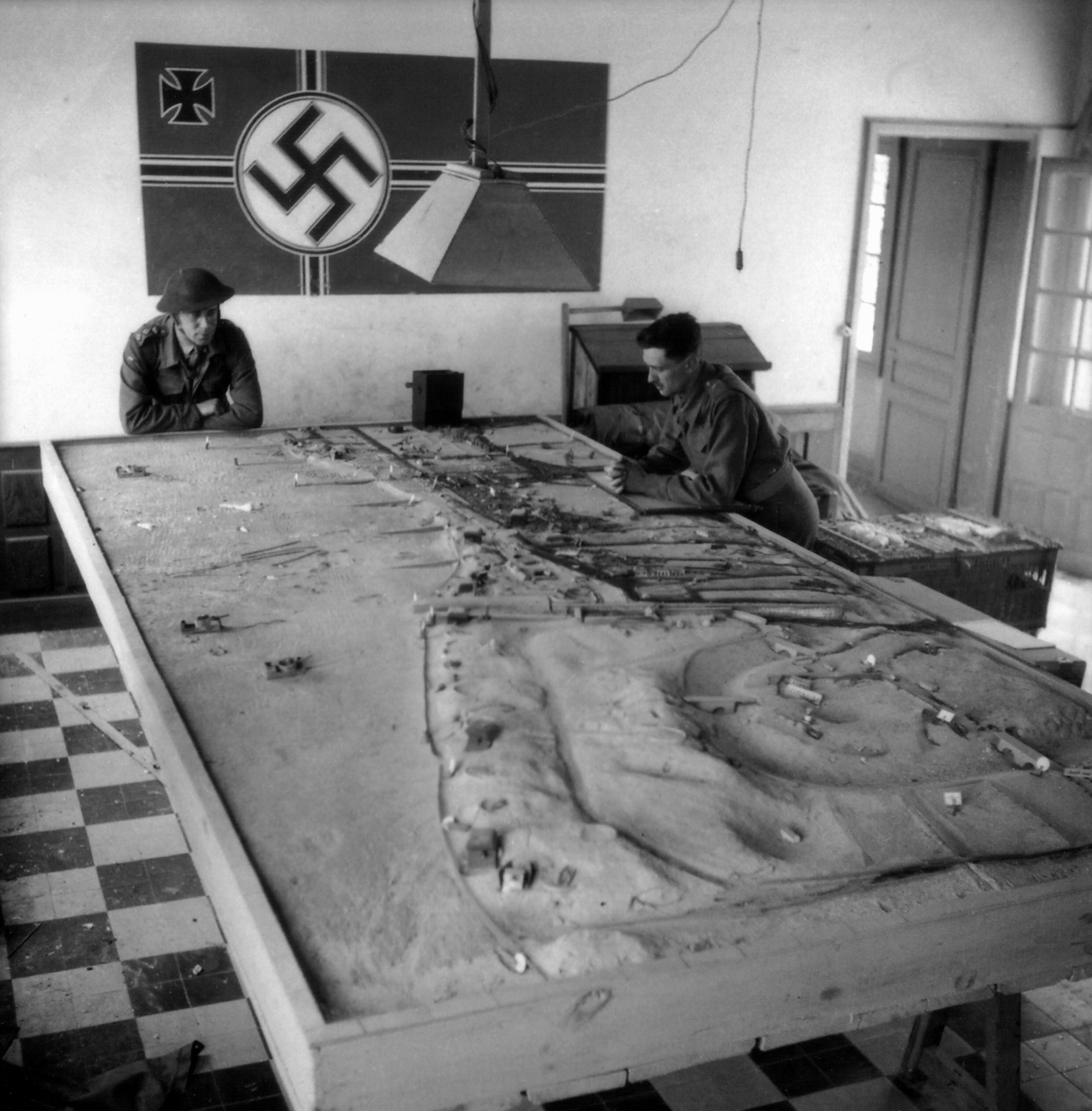 Two Canadian soldiers looking at a German model of defenses at Courseulles sur Mer (Juno Beach), Normandy, France, 6 Jun 1944