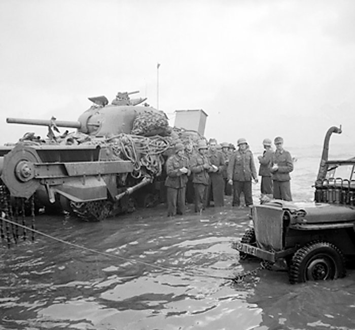 German prisoners awaiting transfer at the beaches of Normandie, France, 6 Jun 1944; note disabled Sherman Crab flail tank in background