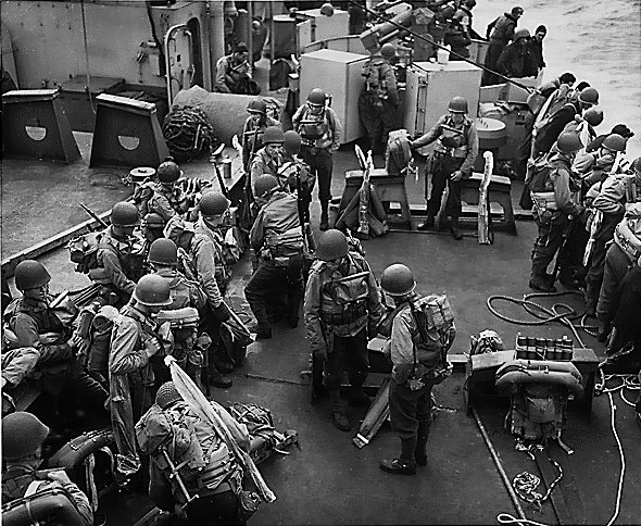 American soldiers in full combat gear on the deck of an United States Coast Guard assault transport in the English Channel, off Normandy, France, 6 Jun 1944