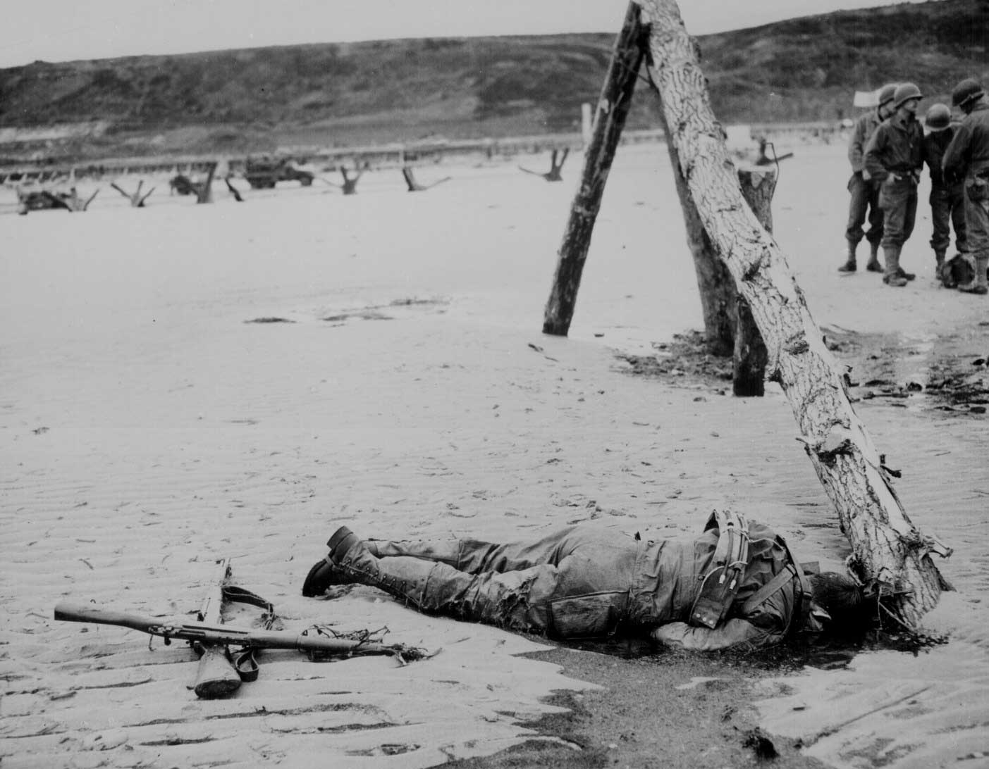 Next to a fallen soldier, a fellow comrade formed a cross with rifles to pay his respects, Normandy, France, Jun 1944