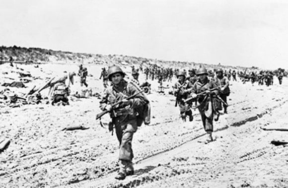 US troops passing along the shore edge in the path of armored vehicles, Normandy, France, 6 Jun 1944