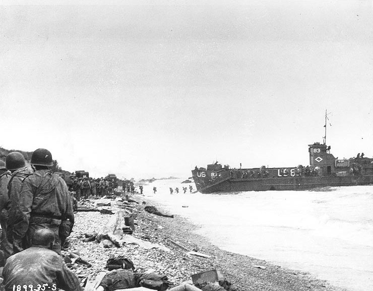 Troops of 3rd Battalion, 16th Infantry Regiment, 1st Infantry Division assembled on Omaha Beach before moving inland near Collville-sur-Mer, 6 Jun 1944; note LCI(L)-83 in background landing more men