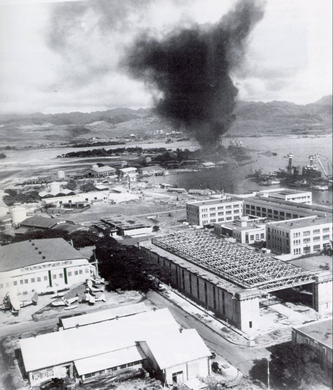 USS Arizona continuing to burn one day after the Japanese attack, Pearl Harbor, US Territory of Hawaii, 8 Dec 1941; note JRS-1 flying boat in left foreground
